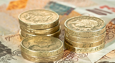 A pile of British pound coins on ten pound notes