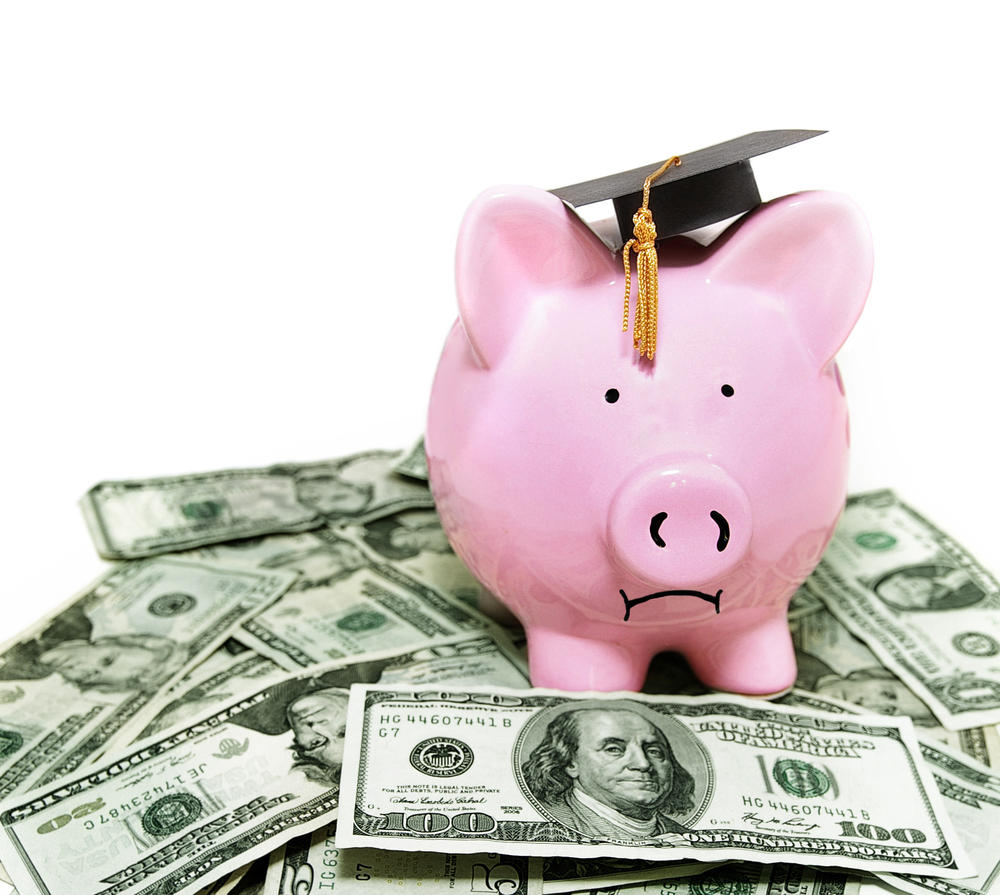 frowning piggy bank with graduation cap, on cash